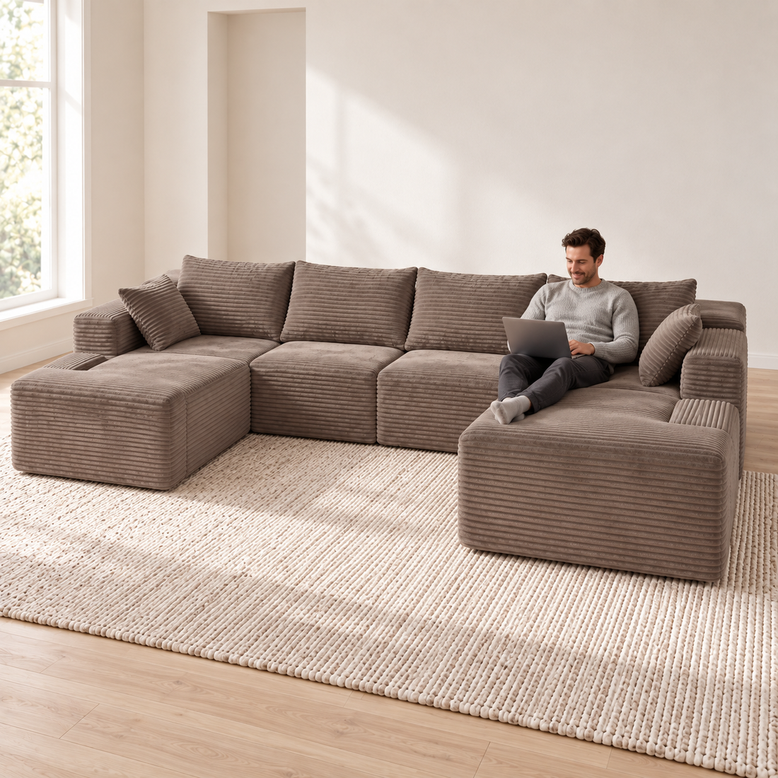Man using a laptop on an oversized taupe corduroy U-sectional